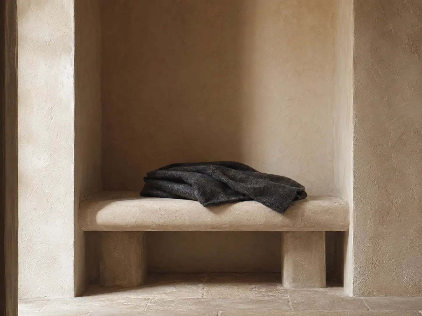 Charcoal wool resting in a protected stone alcove, representing emotional safety