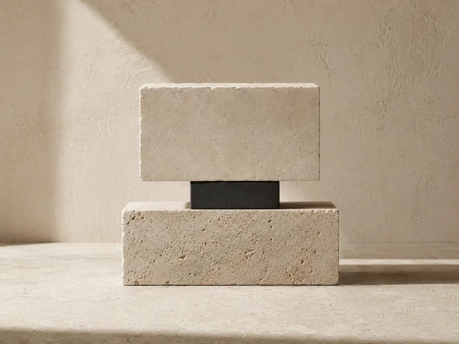 Balanced limestone blocks joined by a charcoal support, representing rebuilding self-worth through structure
