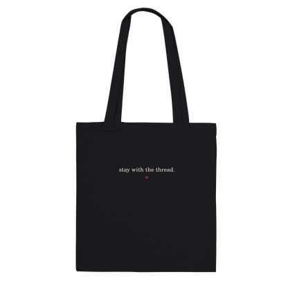 Back of THE THREAD tote featuring the words stay with the thread in ivory lettering.