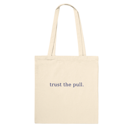 Rear view of THE PULL tote showing the words trust the pull on natural cotton.