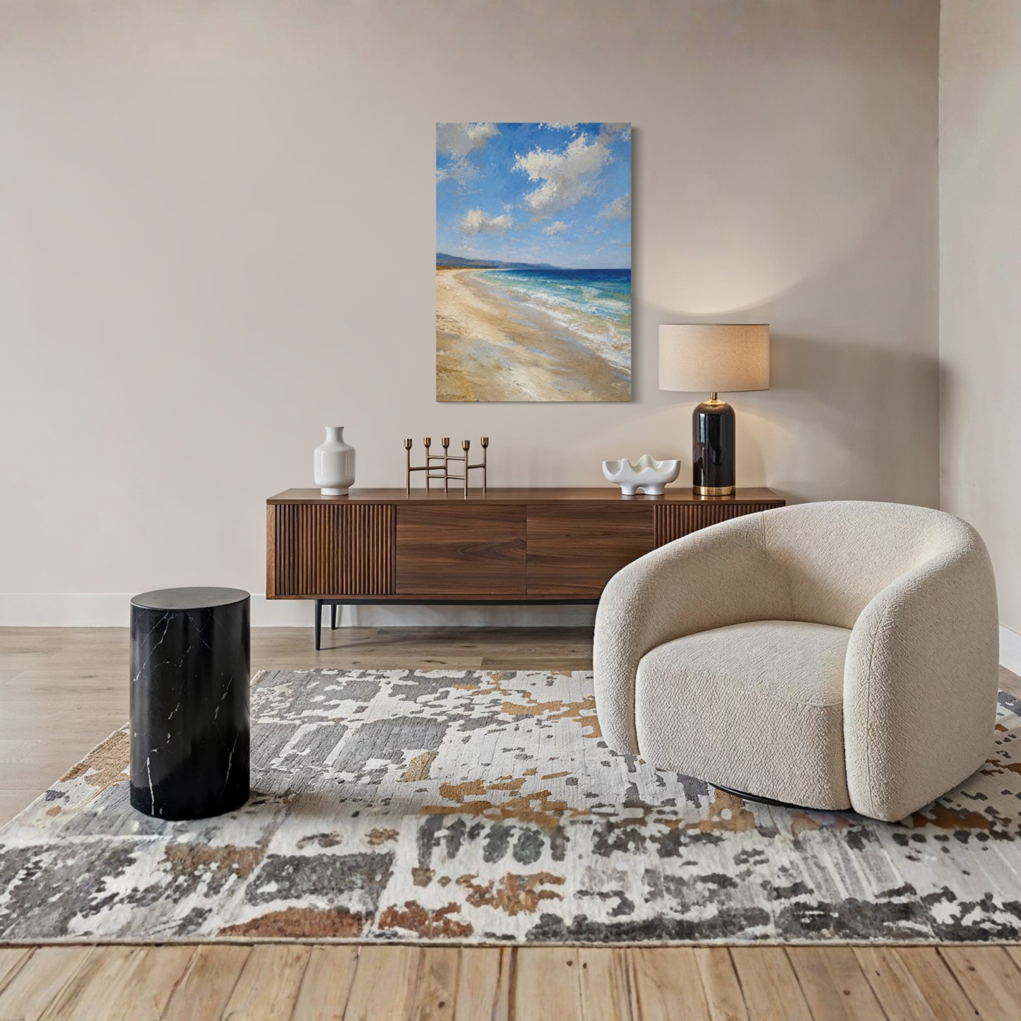 The Blue Distance Mediterranean canvas art hangs on a beige wall above a dark wood sideboard in a styled living room. The room includes a cream boucle armchair, a black marble side table, a patterned rug, and a table lamp.