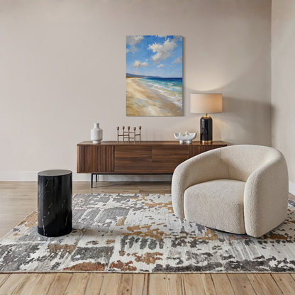 The Blue Distance Mediterranean canvas art hangs on a beige wall above a dark wood sideboard in a styled living room. The room includes a cream boucle armchair, a black marble side table, a patterned rug, and a table lamp.