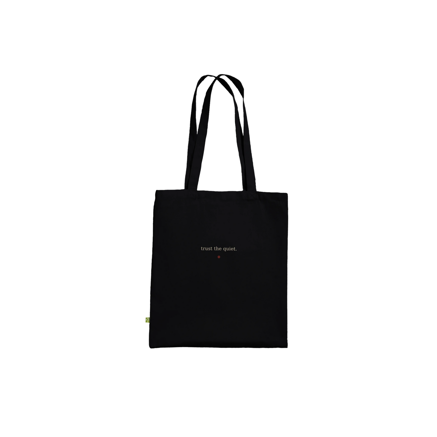 Reverse product view of THE LISTENING black cotton tote with the affirmation trust the quiet printed discreetly.