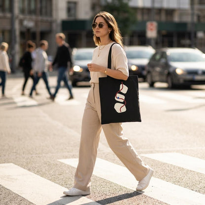 Woman carrying THE THREAD black cotton art tote on a city street.