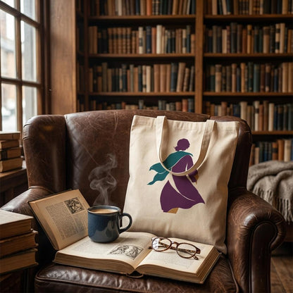 THE TURN natural cotton art tote displayed on a leather armchair beside dark wooden bookshelves.