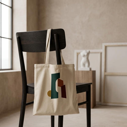 THE THRESHOLD natural cotton art tote hanging from a dark chair in a calm neutral interior.